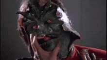 a person is touching a man 's face with a green monster mask .