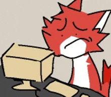 a red and white cat is sitting at a table with a box in its mouth .