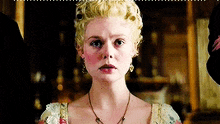 a woman with blonde hair and a necklace is wearing a tiara and earrings .