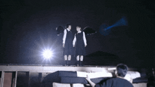 two girls with black wings standing on a roof