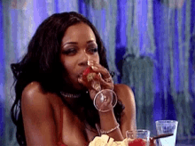 a woman is sitting at a table drinking from a wine glass .