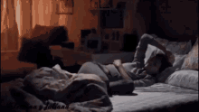 a person is laying on a bed with their arms outstretched in a dark room .