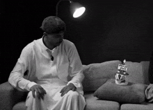 a black and white photo of a man sitting on a couch next to a birthday cake that says happy birthday
