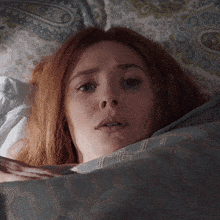 a woman with red hair is laying in bed