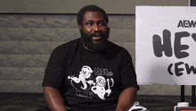 a man sitting in front of a sign that says aew crew
