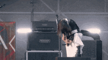 a woman is playing a guitar in front of a mesa amplifier