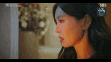 a close up of a woman 's face with sbs written on the bottom right