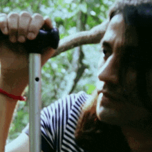 a woman in a striped shirt is holding a pole with her hand