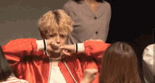 a man in a red jacket holds his hand to his face