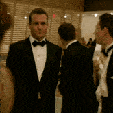 a man in a tuxedo and bow tie is standing in a room