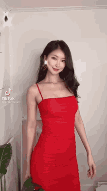 a woman in a red dress is standing in a room and smiling .