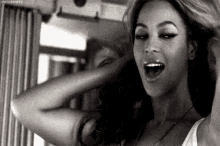 it is a black and white photo of a woman with her mouth open .