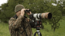 a man looking through binoculars with a camera attached