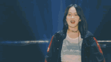 a woman is standing on a stage with a microphone in her hand and making a funny face .
