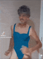 a man in a blue swimsuit is standing in a doorway .