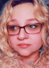 a woman wearing glasses and a necklace looks at the camera