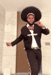 a man in a mariachi outfit is dancing in a doorway