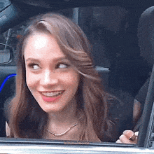 a woman is smiling while looking out of a car window .
