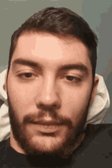 a man with a beard is looking at the camera with his eyes closed