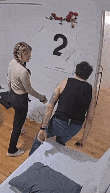 a man and a woman are standing in front of a wall with a calendar with the number 2 on it