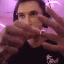 a man wearing headphones and a ring is holding something in his hand .
