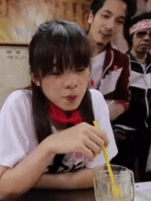 a girl sitting at a table with a straw in her hand