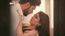 a man and a woman are kissing and looking at each other .