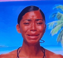 a woman in a bikini is crying in front of a beach .