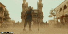 a blurred image of a man standing in front of a building with the words pranay_varma on the bottom