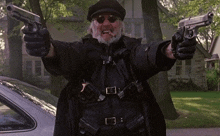 a man in a black coat is holding two guns in his hands