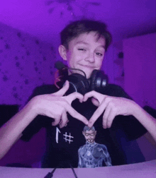a boy wearing headphones makes a heart with his hands