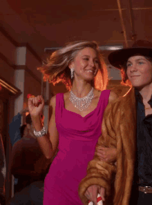 a woman in a pink dress is dancing with a fur coat