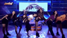 a group of women are dancing on a stage in front of a sign that says showbiz