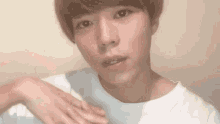 a young man with short hair is wearing a white t-shirt .