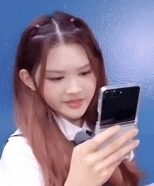 a girl with long red hair is looking at her cell phone