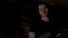 a man in a black shirt is holding a glass of wine in his hand .