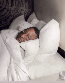 a man laying in bed with his head on a pillow with his eyes closed