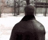 a man in a leather jacket is standing in the snow .