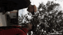 a man in a red jacket is standing upside down in front of trees .