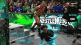 a wrestler is jumping over another wrestler in front of a sign that says restlemania