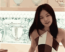 a woman stands in front of a kitchen mixer