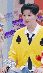 a young man wearing a yellow sweater and tie is holding a microphone