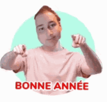 a man in a pink shirt is pointing at the camera and says `` bonne annee '' in a circle .