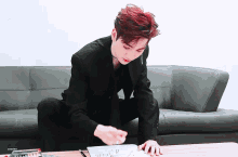 a man with red hair is sitting on a couch with a cherry colored pencil in front of him