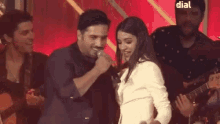 a man is singing into a microphone while a woman stands behind him .