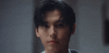 a close up of a young man 's face looking at the camera with a serious look on his face .