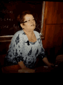 a woman sitting at a desk in front of a blackboard that says ' x + y ' on it