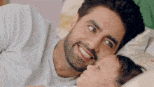 a man is laying in bed with a baby and smiling .