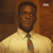 a man in a yellow shirt and blue tie is looking up at something