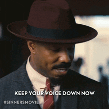 a man in a suit and hat with the words keep your voice down now below him